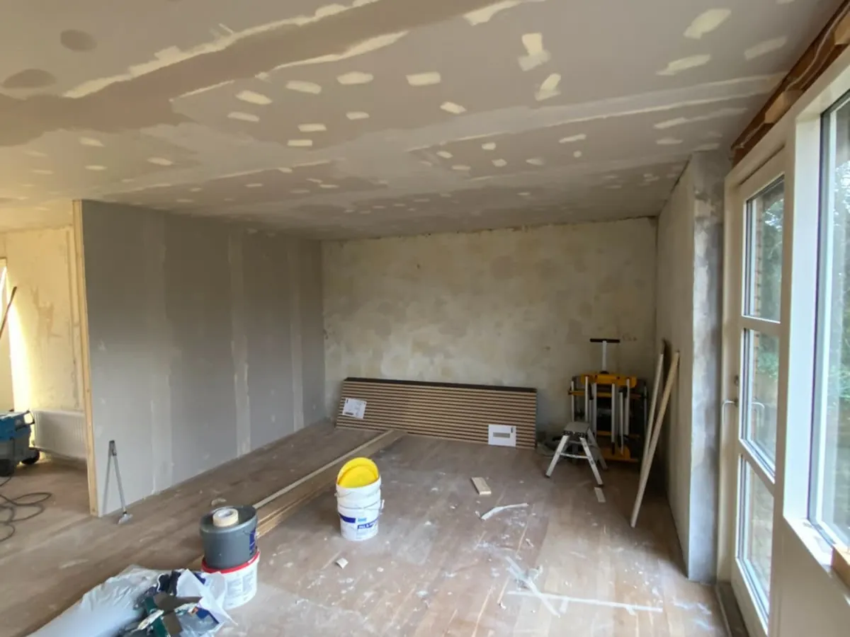 Stue under renovering med rå gipsvægge før maling