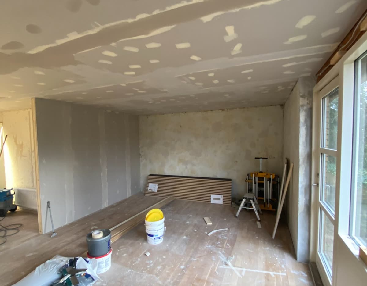 Stue under renovering med rå gipsvægge før maling